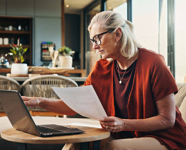 Woman sitting at a table with a computer reviewing paperwork